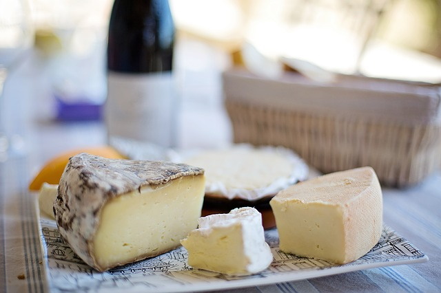 Assorted cheeses on a plate with a bottle of wine